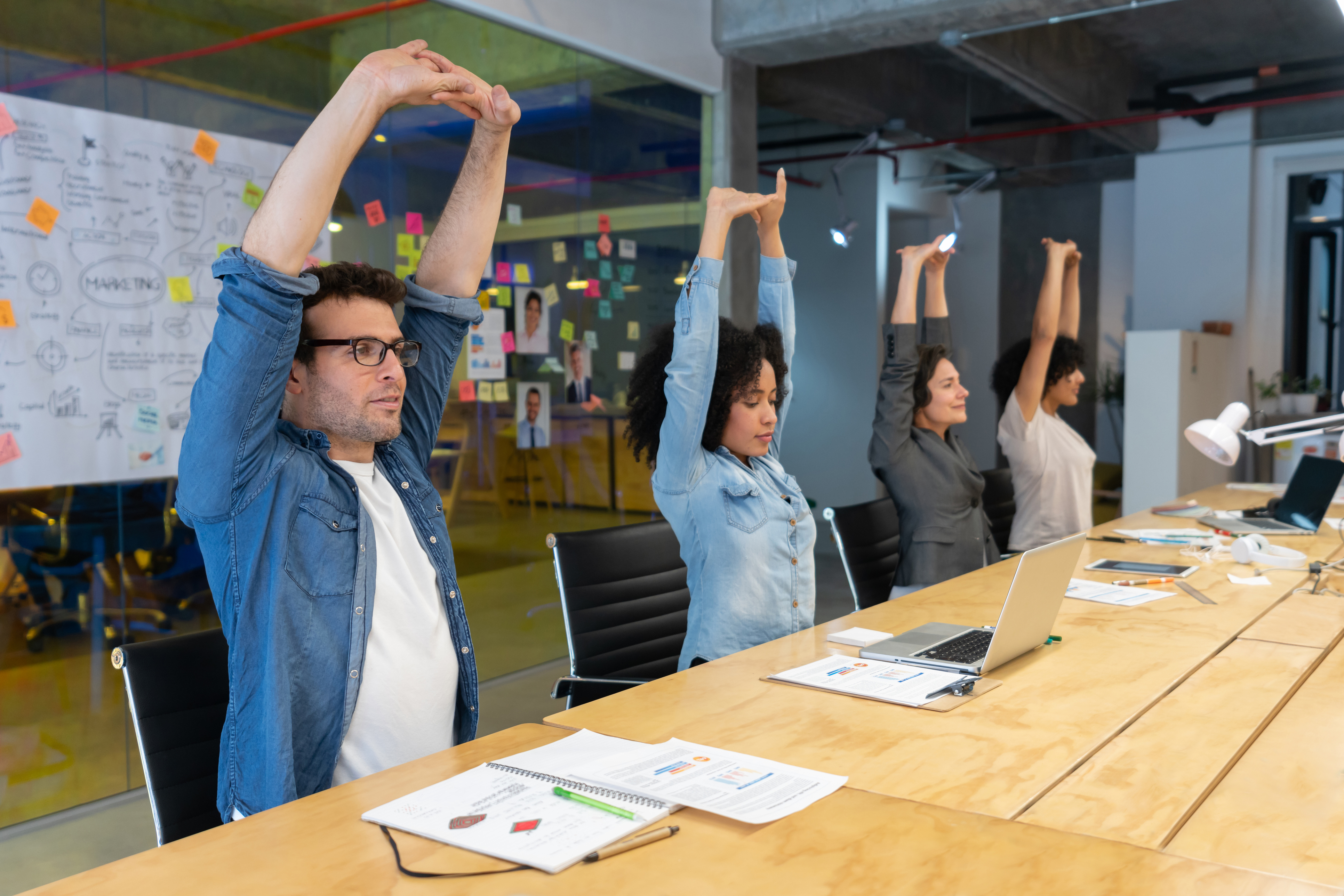 Employees stretching in office meeting for worksite wellness