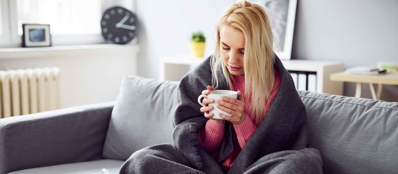 Woman on couch sick with blanket