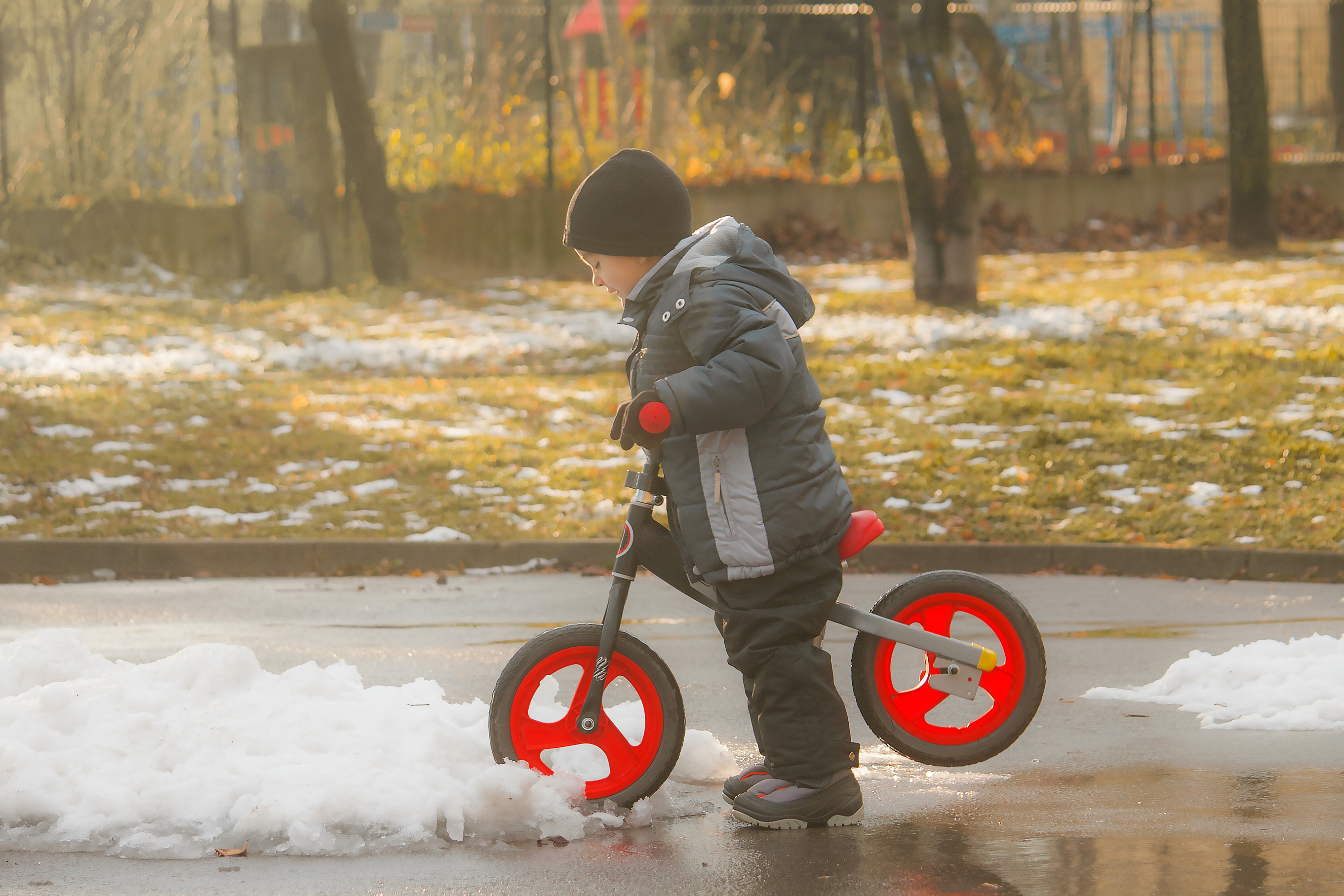 Kid playing with bike in melting snow