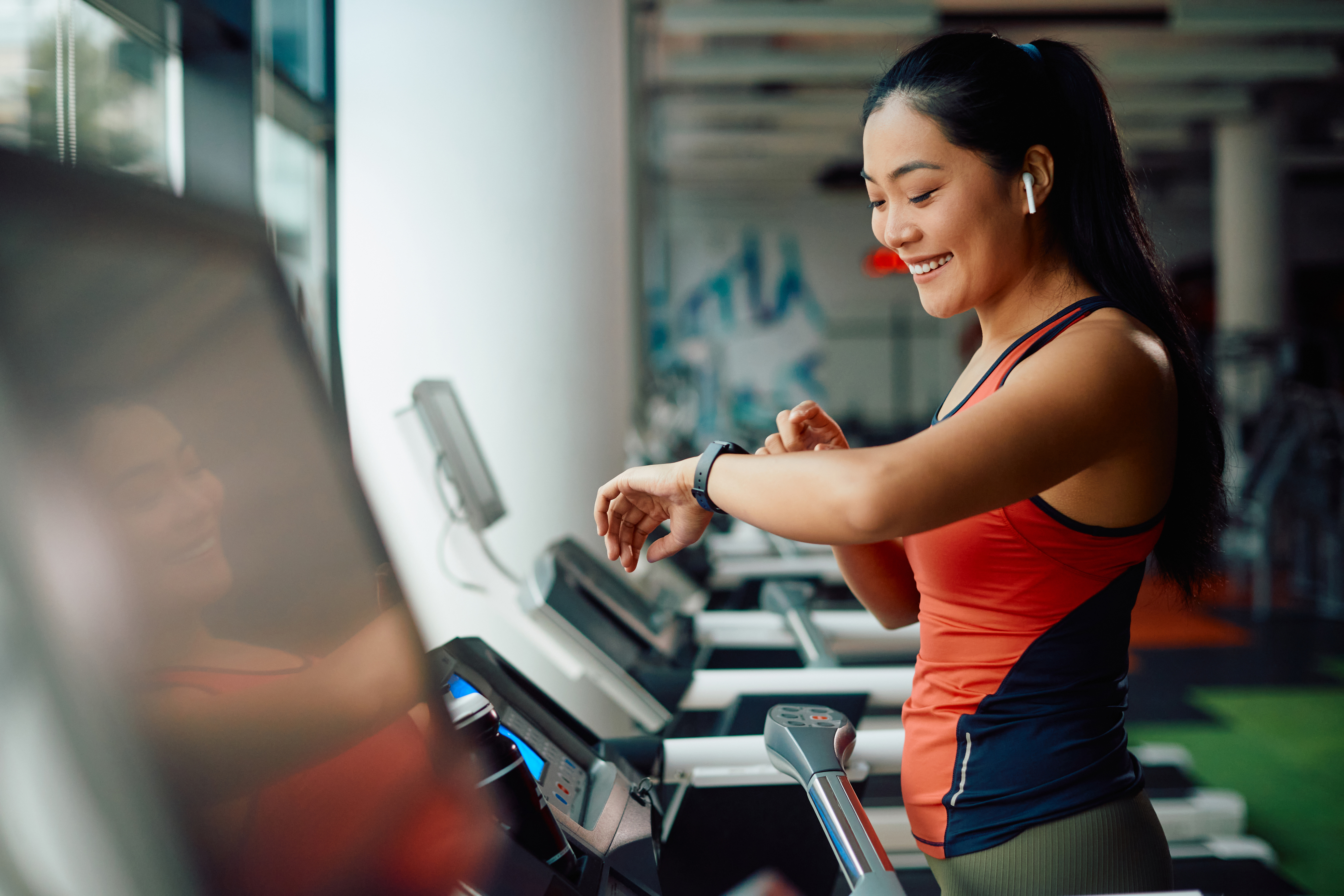 Athletic woman using fitness tracker while running on treadmill