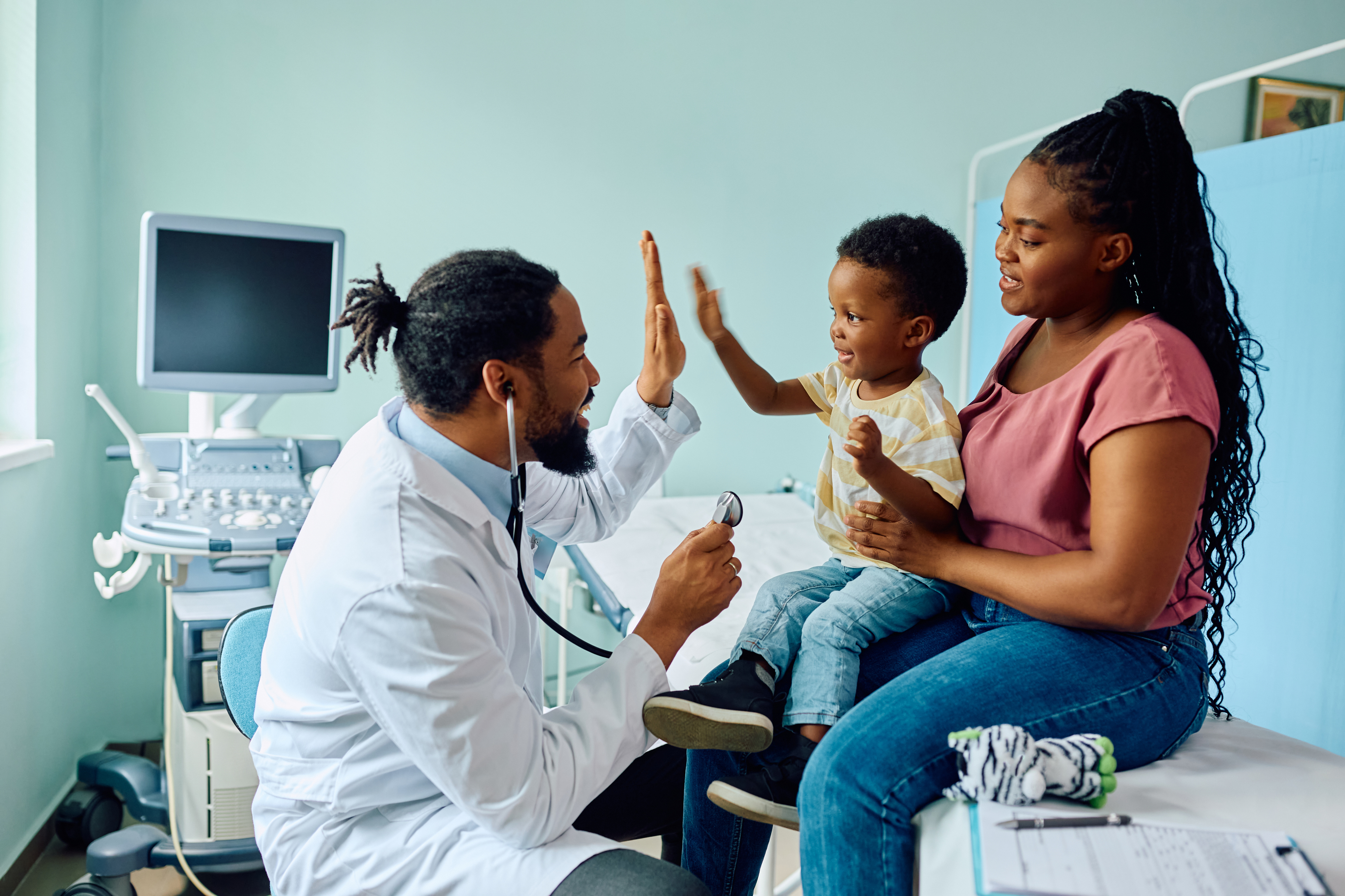 boy giving high five to his pediatrician after medical examination at doctor's office