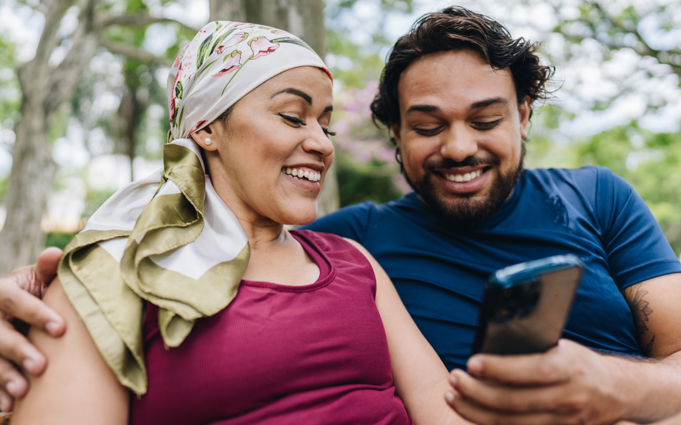 man and woman sit together outside using a phone