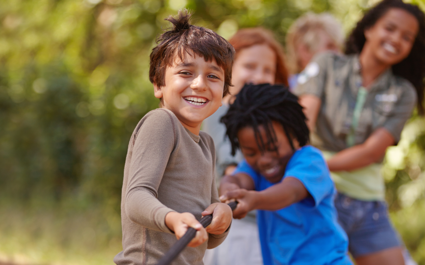 group of kids playing tug of war with a rope outside