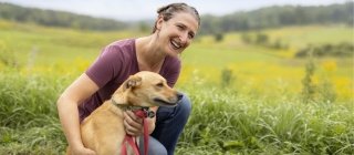 Female sitting in a field with her dog