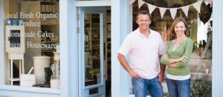 Two business owners standing in front of their store