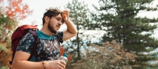 Man feeling overheated on walk with a water bottle