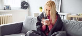 Woman on couch sick with blanket