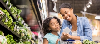 Mother and daughter looking at list while grocery shopping