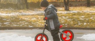 Kid playing with bike in melting snow