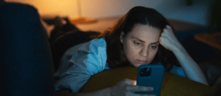 woman looking at her phone in bed at night