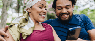 man and woman sit together outside using a phone