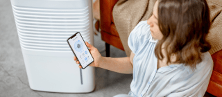 woman using an air purifier and app to control it