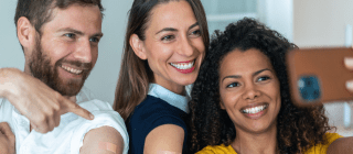 three adult friends taking a selfie together after getting vaccinated
