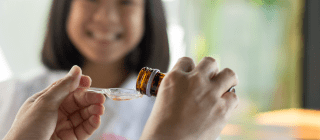 hands pouring a dose of medicine for a smiling child
