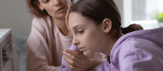 child looking upset with mother in the background