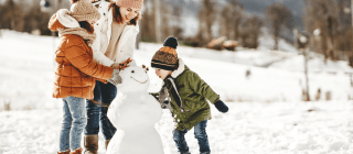 adult and two kids building a snowman