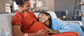 pregnant mom sitting on couch with daughter