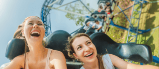 Two women riding roller coasters