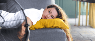 woman laying on the couch in front of a fan 