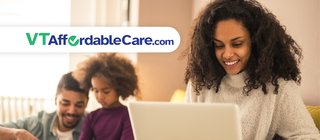 Woman looking at computer with family in background