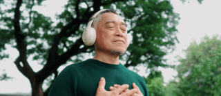 man meditating outside wearing headphones