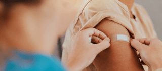 woman applying a bandaid to an arm after a vaccine