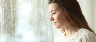 young woman looking out a window during winter