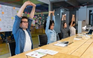 Employees stretching in office meeting for worksite wellness