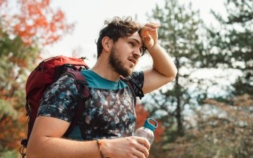 Man feeling overheated on walk with a water bottle