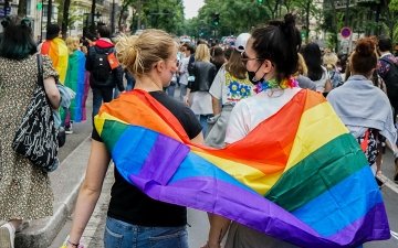 Two women walking in pride parade with pride flag