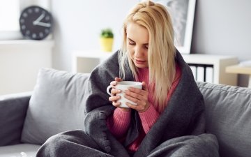 Woman on couch sick with blanket