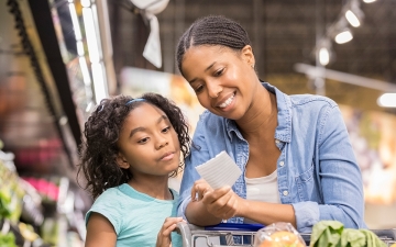 Mother and daughter looking at list while grocery shopping