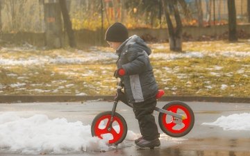 Kid playing with bike in melting snow