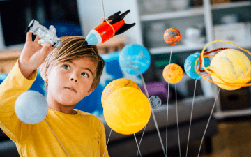young boy playing with space-themed toys