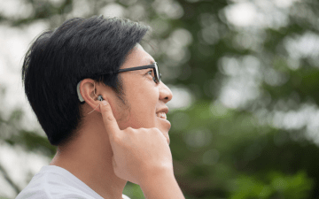 man standing outside pointing to his hearing aid