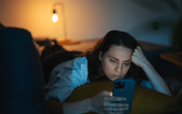 woman looking at her phone in bed at night