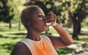 woman taking an inhaler outside