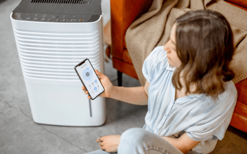 woman using an air purifier and app to control it