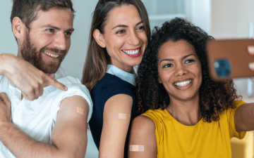 three adult friends taking a selfie together after getting vaccinated