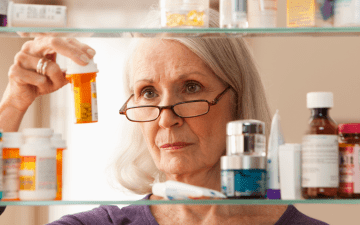 woman looking at prescriptions in medicine cabinet