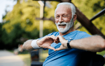 man sitting on a bench making a heart symbol with his hands