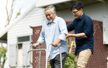 man acting as a caregiver to another man with a walker