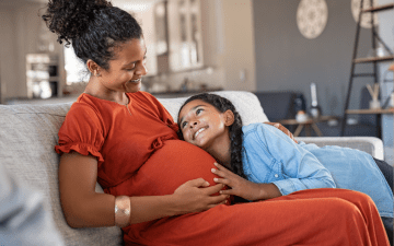 pregnant mom sitting on couch with daughter