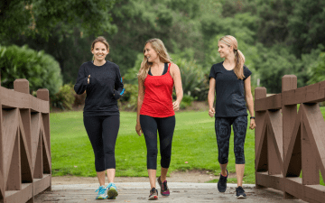 three women walking across a bridge