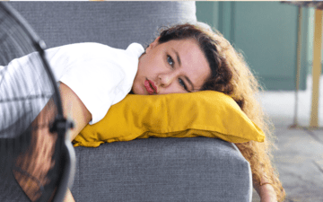 woman laying on the couch in front of a fan