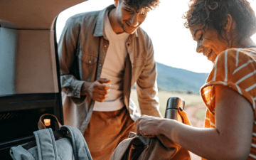 A couple packs their backpacks in the back of a car before a hike