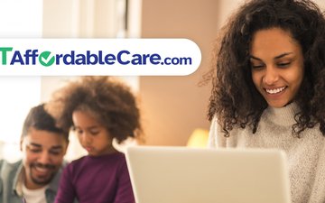 Woman looking at computer with family in background