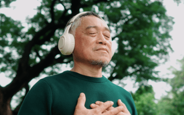 man meditating outside wearing headphones