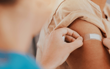 woman applying a bandaid to an arm after a vaccine