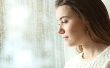 young woman looking out a window during winter